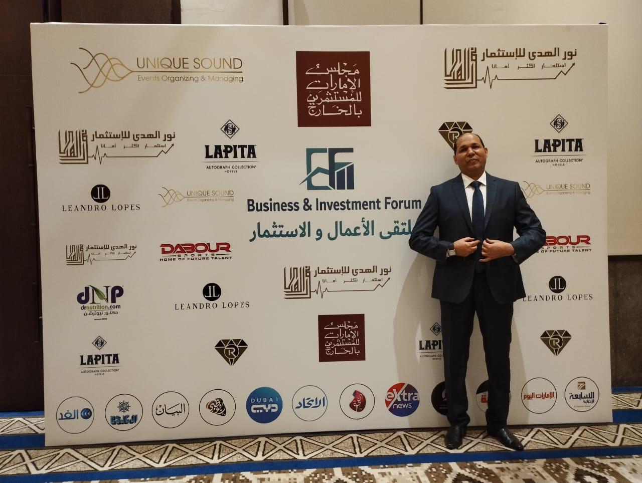 Attendee standing in front of the Business & Investment Forum sponsor backdrop