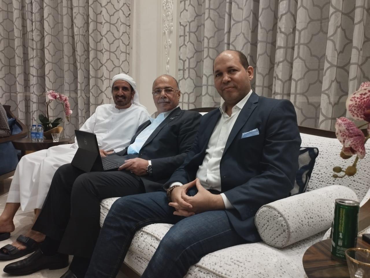 Three organisers seated on a sofa reviewing forum plans on a laptop